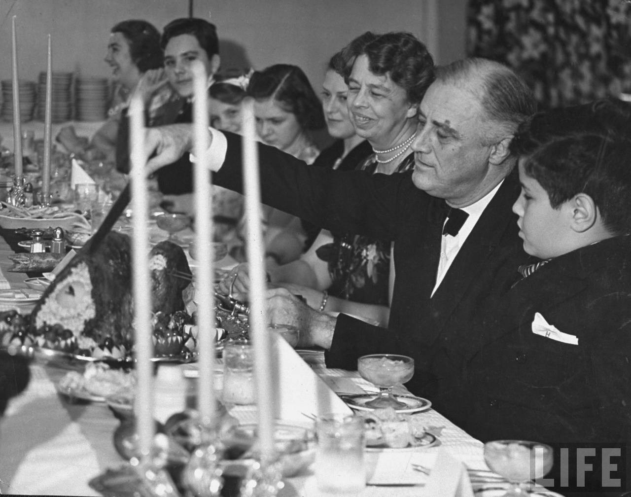 Pres. Franklin D. Roosevelt w. his wife Eleanor, serving Thanksgiving turkey to polio patients who drew lots to see who would sit at the Pres.s table in Georgia Hall at Warm Springs Foundation. Photographer:Margaret Bourke-White. © Time Inc